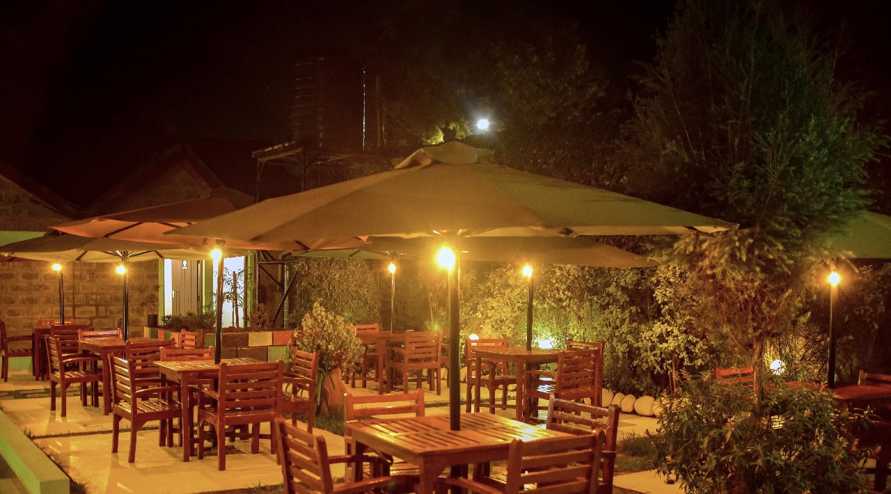 Shades Restaurant garden at night — tables under a glowing umbrella, Nanyuki